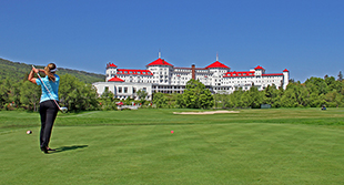 Woman tees off with Mount Washington Hotel in background